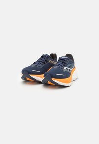 Et par marineblå og oransje atletiske løpesko med svarte såler og Saucony-logo på siden, sett forfra på hvit bakgrunn.