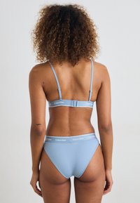 Lys blå bikini-sett med justerbare stropper og logoband. Enkelt design, glatt tekstur og klassisk kutt for både topp og bunn.