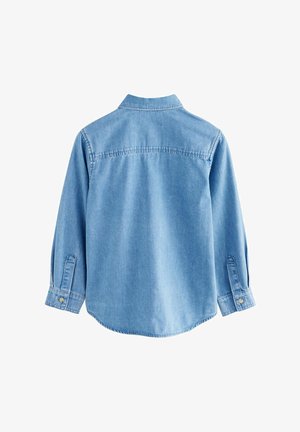 Šviesiai mėlynas džinsinis marškinis, ilgomis rankovėmis su sagomis ant rankogalių, kriauklės apykakle, nugaros jungties siūle ir kreivu apačios kraštu. Lygus paviršius su silpna medžiagos tekstūra.