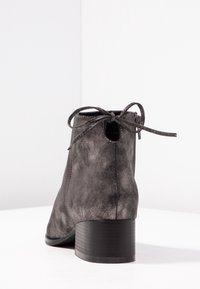 Šedá semišová kotníková bota s oblým špičkou, malým podpatkem a dekorativní mašlí vzadu, s výřezem nad patou.