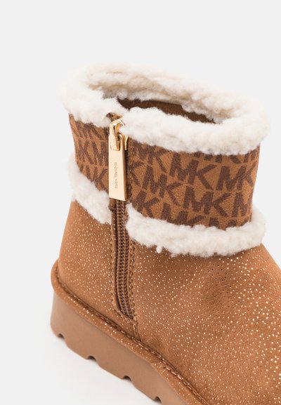 Brown ankle boot with a shiny finish, faux fur lining, and a patterned textile upper. Features a side zipper and textured sole.