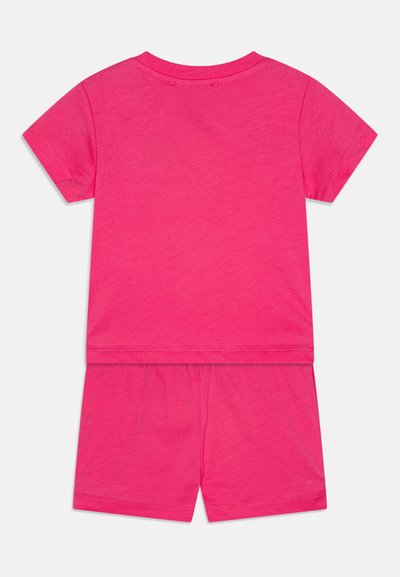 Top de algodón rosa de manga corta con pantalones cortos a juego. Textura suave, diseño sencillo, escote redondo y bordes rematados.