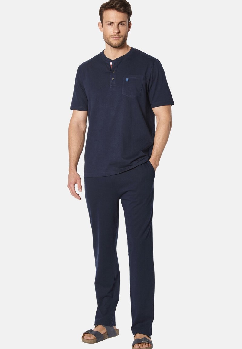 Navy cotton short-sleeve top with a pocket and button placket, paired with matching pants and brown sandals. Smooth texture, relaxed fit.