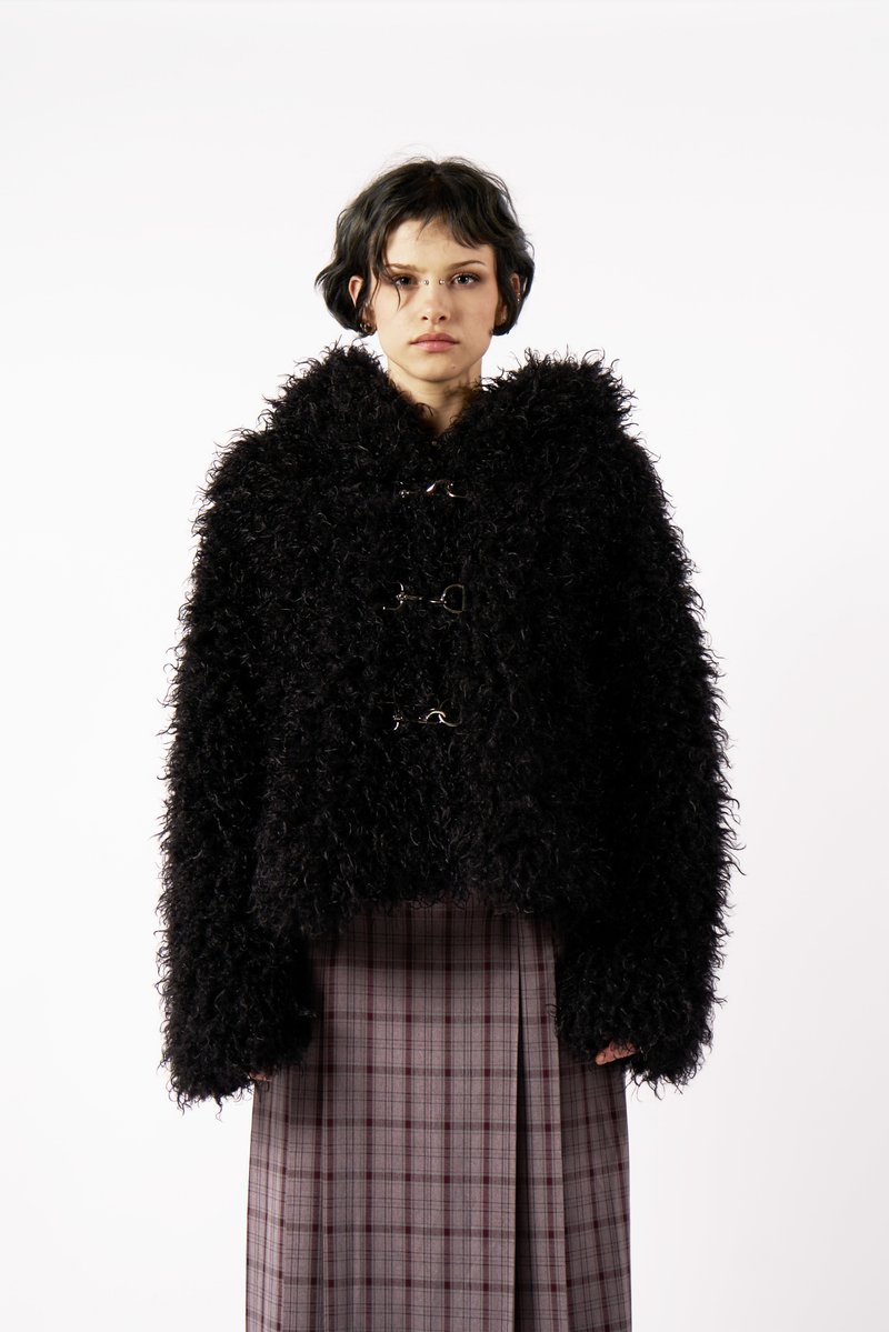 Fekete, bolyhos kabát, textúrált anyagból, rövidített fazonnal, csőnyakkal és elöl ezüstszínű csuklókkal.