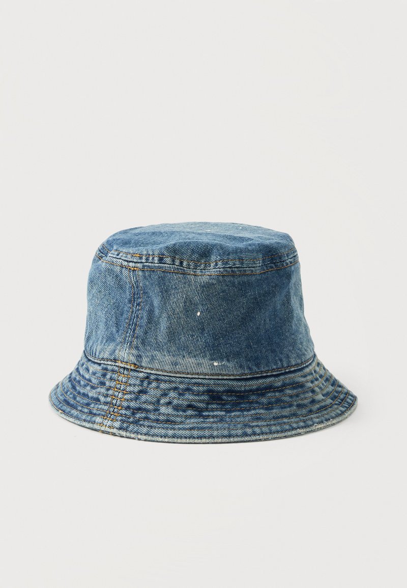 Denim bucket hat met vervaagde blauwe kleur, zichtbare stiksels en kleine verfvlekken op een effen witte achtergrond.