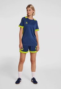 Tenue de sport bleu marine comprenant un haut à manches courtes et un short avec des accents vert citron, design sportif, matériau respirant et détail du logo.