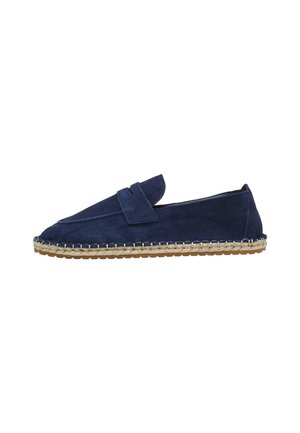 Chaussure slip-on en suède bleu marine avec une semelle en jute cousue et une sangle décorative à l'avant. Bout rond et design à profil bas.