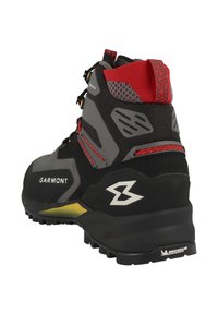 Bota de senderismo en negro y gris con un upper texturizado, acentos rojos y una suela robusta con dibujos profundos, diseñada para la durabilidad y la tracción.