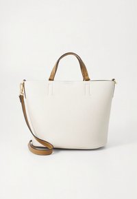 Sac fourre-tout blanc texturé avec poignées en cuir marron et une bandoulière ajustable. Présente un design minimaliste et des accents en métal doré.