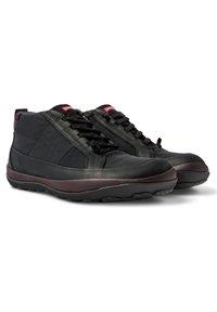 Scarpe alte nere con tomaia in pelle liscia e tessuto resistente, suola a contrasto color bordeaux, dotate di lacci e collo della caviglia imbottito.