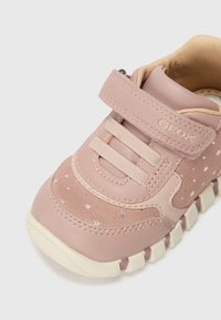 Chaussure pour enfant en cuir rose et en suède avec des motifs d'étoiles, lacets élastiques, sangle réglable et semelle en caoutchouc texturée.