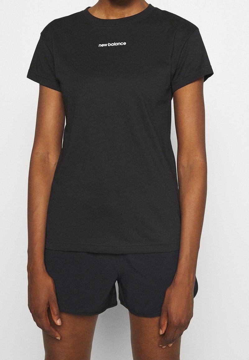 Camiseta negra de algodón con mangas cortas, con un logo blanco de "new balance" en el pecho. Combinada con pantalones cortos deportivos negros.