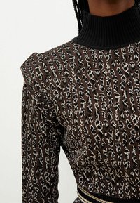 Maglione con stampa leopardata marrone e nera, colletto alto a coste nere e dettagli con spalle a palloncino.