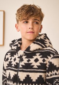 Felpa con cappuccio con motivo geometrico crema e nero, con zip frontale e tessuto morbido e testurizzato per il calore.