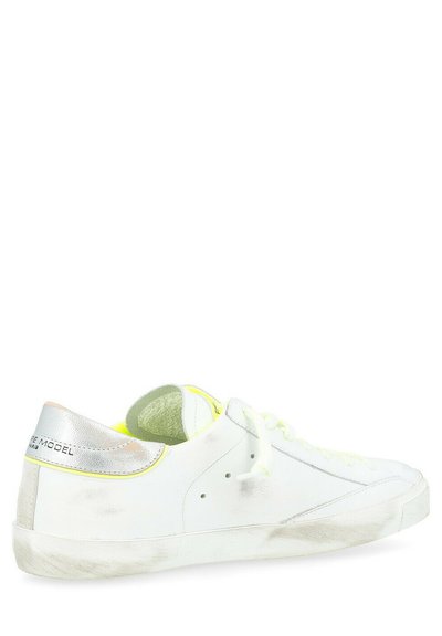 Sneaker in pelle bianca con texture liscia, tallone metallic silver e dettagli in neon giallo. Chiusura con lacci bianchi e suola in gomma.