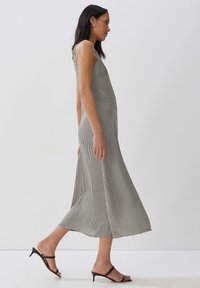 Schwarz-weiß kariertes Midi-Kleid mit tailliertem Oberteil und ausgestellt geschnittenem Saum, gefertigt aus leichtem Stoff. Verfügt über ein ärmelloses Design und seitliche Taschen.
