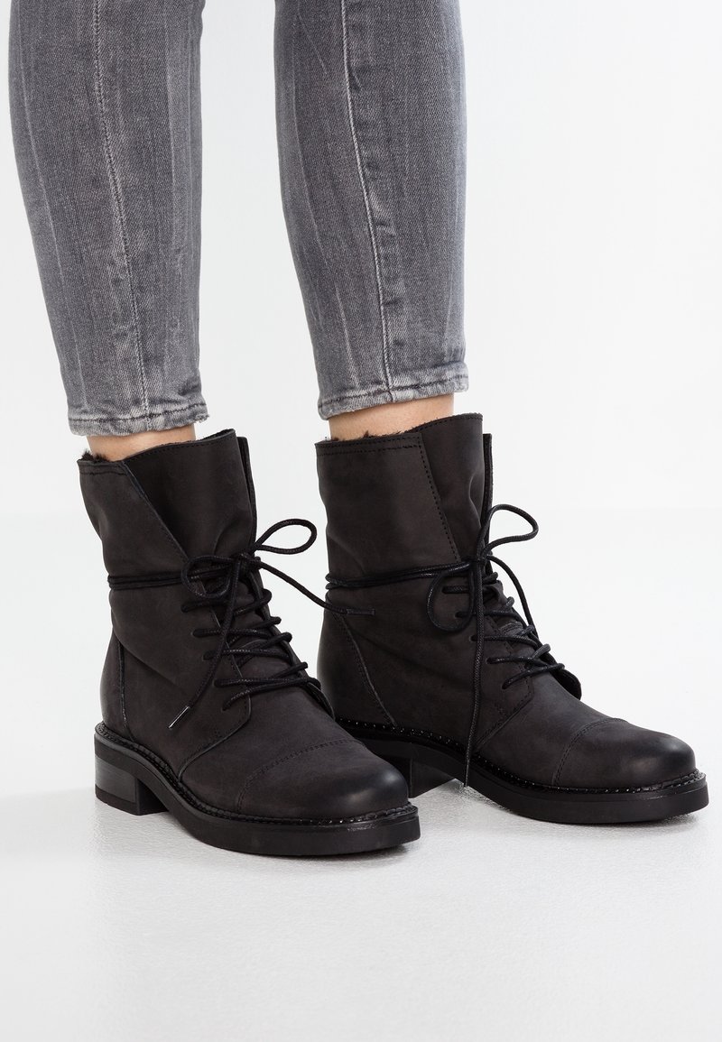 Bottes noires à la cheville en cuir lisse avec un bout arrondi, un talon plat et des lacets ; présentent des coutures discrètes et une bordure supérieure texturée.