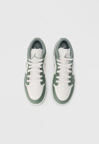 Zelené a biele tenisky s hladkým koženým vrchom a perforovanou špičkou, s bielymi šnúrkami a textúrovaným golierom, s logovými akcentmi na bokoch.