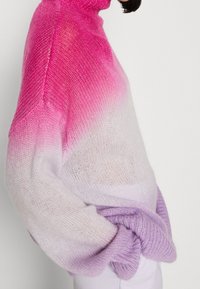 Pull en tricot ombré avec un col montant, dégradé du rose au blanc, et violet à l'ourlet, avec des manches larges et amples.