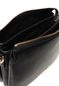 Borsa a mano in pelle nera con una cerniera dorata, dotata di due scomparti interni e un'esterno liscio e testurizzato. Dettaglio del logo visibile nella parte inferiore.