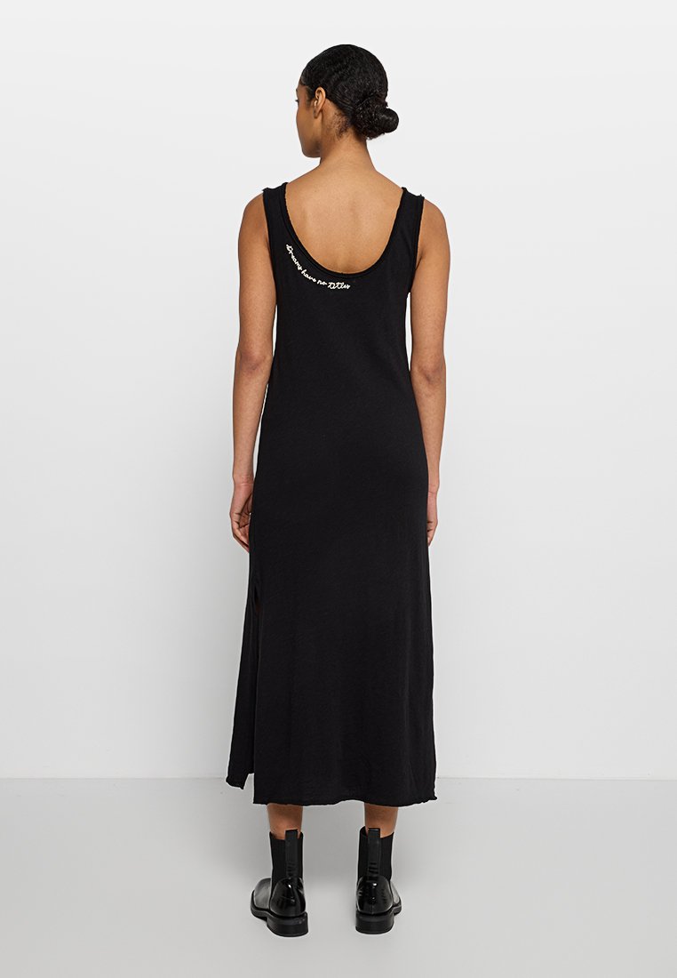 Schwarzes, ärmelloses Maxikleid mit kurviger Rücken-Ausschnitt aus weichem Stoff, mit seitlichem Schlitz und kontrastierendem Textdetail auf der Rückseite.
