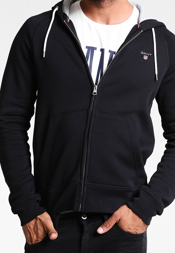 Felpa nera con zip e cappuccio foderato in grigio, dotata di un piccolo logo sul petto, tasche frontali e polsini e orlo a costine.