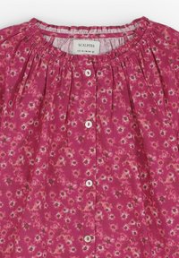 Blusa floral rosa con escote fruncido, mangas cortas y cierre de botones. Presenta pequeños patrones florales blancos y una tela con textura sutil.