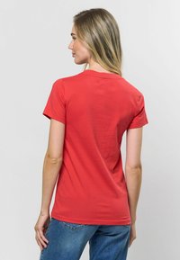 Sarkans kokvilnas T-krekls ar īsām piedurknēm un apļa kaklu, ar gludu tekstūru un pieguļošu griezumu, redzams no aizmugures ar vienkāršu dizainu.