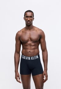 Fekete pamut boxer alsónadrág fehér Calvin Klein logóval a derékszíjon, testhez simuló kialakítással, sima felülettel és látható minták nélkül.