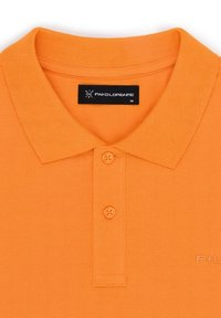 Pomarańczowa koszulka polo o teksturowanym wykończeniu, z dwoma guzikami przy kołnierzyku oraz czarną metką marki. Materiał wydaje się przewiewny i swobodny.
