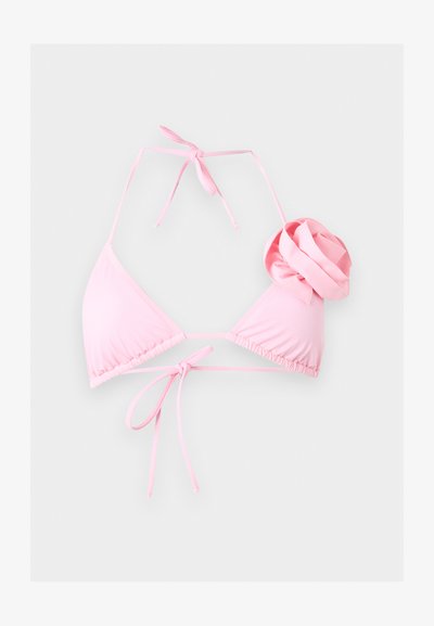 Απαλό ροζ τρίγωνο μπικίνι τοπ με κορδόνια στον λαιμό και ύφασμα λουλούδι σε ένα κύπελλο.