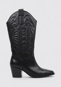 Botte de cow-boy en cuir noir avec un bout pointu, des coutures décoratives sur la tige et un talon empilé. Dotée d'une languette en haut.