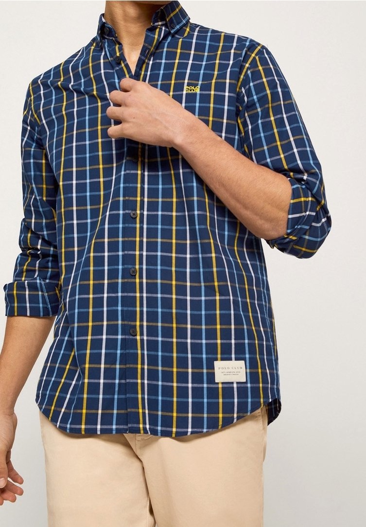 Modrá kostkovaná košile se žlutými a bílými akcenty, dlouhé rukávy s ohrnutím k loktům, knoflíková léga a štítek na dolním pravém rohu.