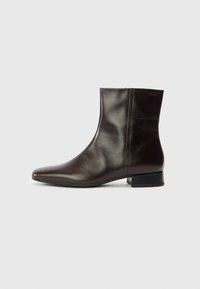 Καφέ δερμάτινο μποτάκι αστραγάλου με μυτερή μύτη, λεία υφή, μεσαία τακούνια και απλό σχέδιο. Μινιμαλιστικό στιλ χωρίς διακοσμητικά.