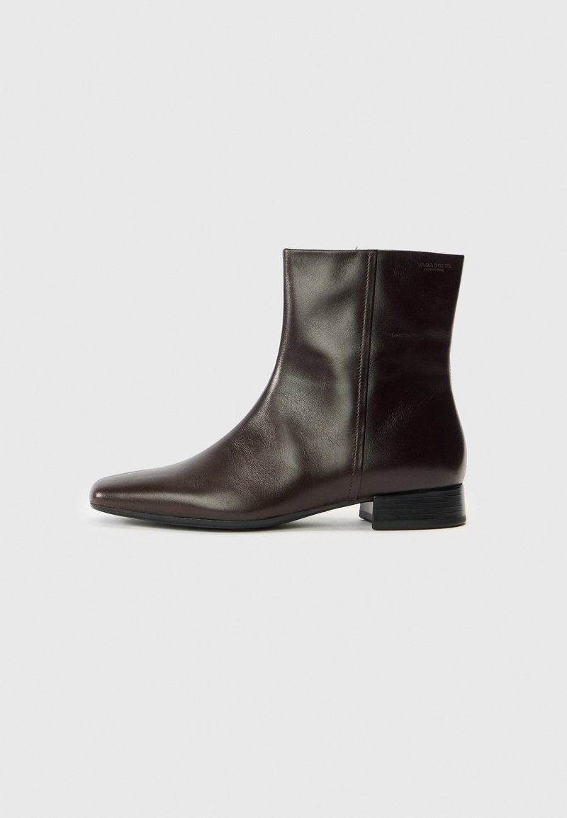 Καφέ δερμάτινο μποτάκι αστραγάλου με μυτερή μύτη, λεία υφή, μεσαία τακούνια και απλό σχέδιο. Μινιμαλιστικό στιλ χωρίς διακοσμητικά.