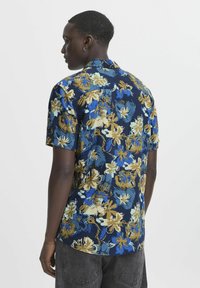 Cămașă cu mânecă scurtă de culoare bleumarin cu un model floral în nuanțe de galben, albastru și verde. Are guler și un tiv drept. Fabricată din țesătură textilă.