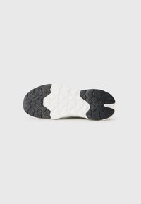 Shoe sole with a black rubber heel and white midsection. Textured pattern provides grip, featuring various shapes for traction.