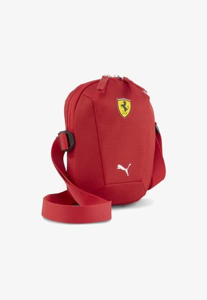 Red fabric crossbody bag with a textured surface, featuring a Ferrari logo and a white Puma logo, includes a detachable strap and zip closure.