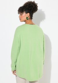Maglione oversize verde chiaro in morbido tessuto, con maniche lunghe e scollatura ampia, caratterizzato da una vestibilità rilassata e orlo a coste.