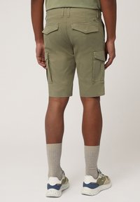 Khaki cargoshorts met meerdere zijzakken, platte achterzakken en een rechte snit, gedragen met lichtgrijze sokken en multikleurige sneakers.