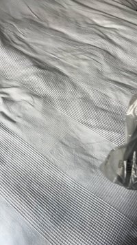 Texturált fehér ágytakaró váltakozó széles és keskeny csíkos mintázattal, puha, sima anyagból készült, finom fényességgel.