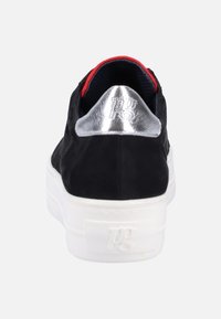Černá sneaker s hladkým textilním svrškem, stříbrný akcent na patě, červená vnitřní podšívka a bílá gumová podrážka s vyraženým logem na boku.