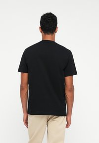 Camiseta de algodón negra con cuello redondo clásico y mangas cortas, con un corte recto y una textura suave.