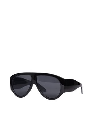 Occhiali da sole neri oversize con montature spesse e lenti scure, mostrati con un leggero angolo su sfondo bianco.