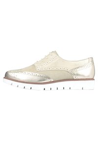 Scarpa beige chiaro con accenti metallici, dettagli brogue e suola in gomma bianca. Texture liscia con punta arrotondata e design con lacci.