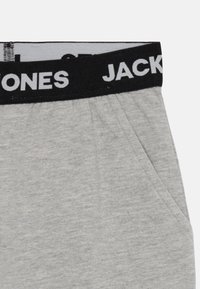Hallid hallid puuvillased lühikesed püksid musta elastse vööga, millel on valge "JACK & JONES" tekst ning küljetaskud lisafunktsionaalsuse jaoks.