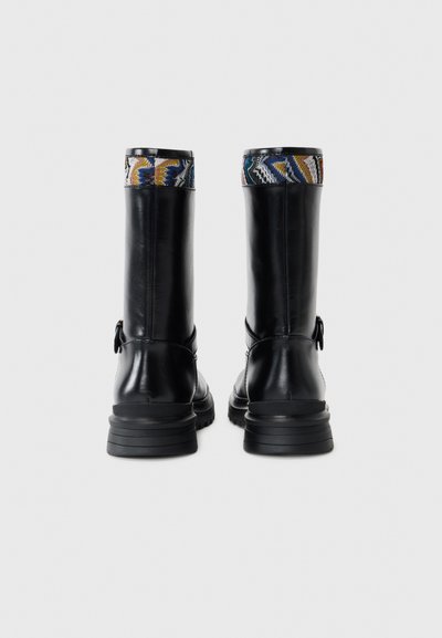 Black leather boots with a textured, patterned cuff. Features a sturdy sole and a smooth finish, secured with a side strap detail.