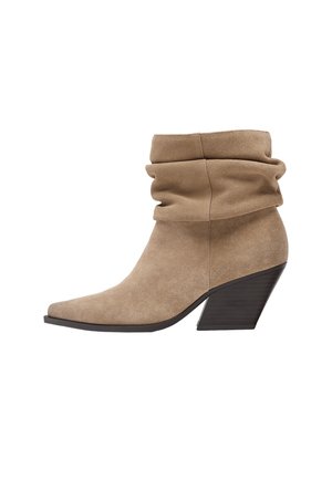 Stivaletto beige in suede con gambale morbido, punta appuntita e tacco in legno impilato inclinato.
