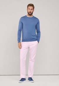 Blauwe longsleeve trui gecombineerd met lichtroze broek en blauwe sneakers. Eenvoudig ontwerp met een getailleerde vorm, gladde textuur en effen kleuren.
