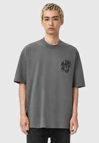 Szara koszulka z krótkim rękawem wykonana z bawełny, z okrągłym dekoltem i nadrukowanym logo na lewej stronie klatki piersiowej. Luźny krój.